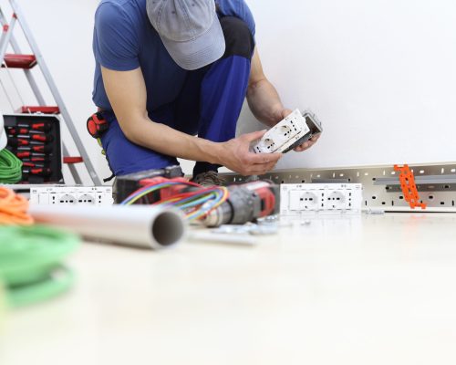 electrician at work with socket in hand, install electric circuits, electrical wiring